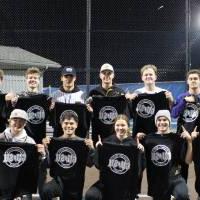 Students holding up championship shirts from a softball tournament